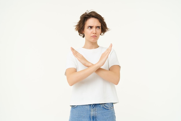 Photo gratuite l'image d'une femme exprime son aversion, montre un geste d'arrêt croisé désapprouve quelque chose d'interdit se tient debout