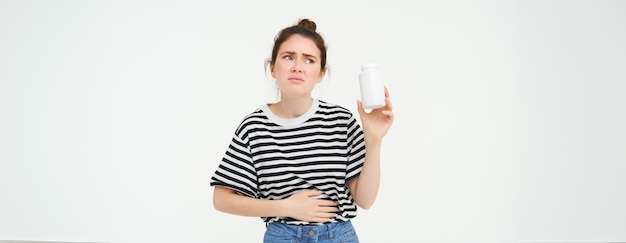 Photo gratuite l'image d'une femme avec des maux d'estomac montre une bouteille avec des pilules prend un comprimé pour les crampes menstruelles