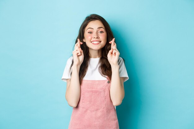 Image d'une femme pleine d'espoir excitée tenant les doigts croisés anticipant de bonnes nouvelles en attente de résultats ma