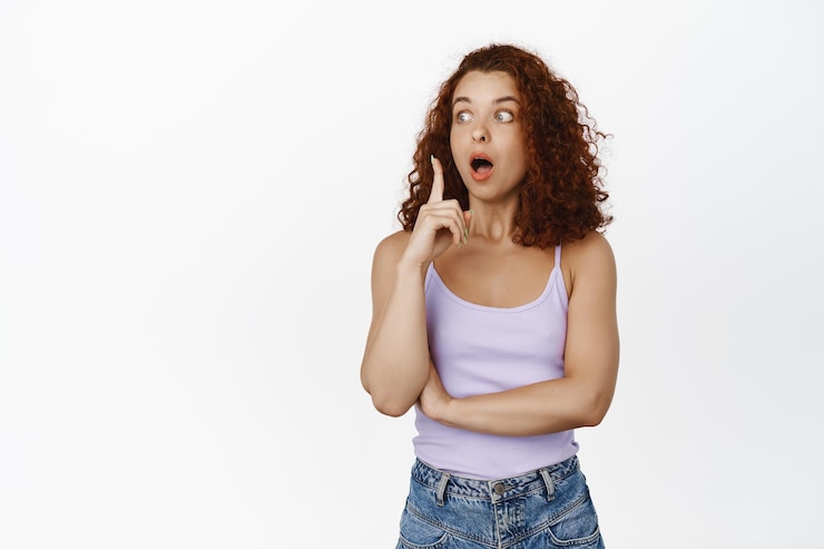 Photo gratuit image d'une femme rousse excitée qui lance une idée, lève le doigt et halete étonnée, a un plan, suggérant qch, a une solution, debout sur fond blanc