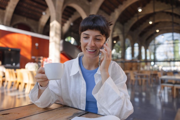 Image d'une femme souriante parlant au téléphone dans un café