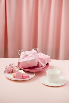 Image de la fête des mères/femme heureuse d'une tasse de café ou de thé et d'une fleur de lisianthus avec un macaron et des cadeaux à côté sur des rideaux de rose.