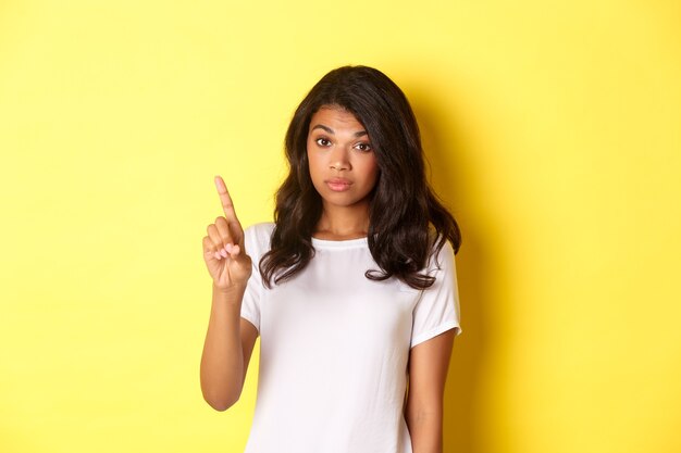 Image d'une fille afro-américaine sérieuse réprimandant quelqu'un levant un doigt et faisant une déclaration