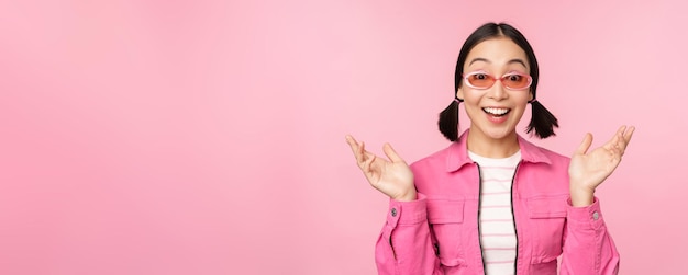 Image d'une fille asiatique qui a l'air surprise et excitée souriante réaction étonnée aux grandes nouvelles debout sur fond rose