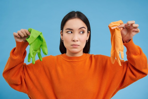 Photo gratuite image d'une fille au visage gêné montrant deux gants de nettoyage sales trouvés des ordures à la déception