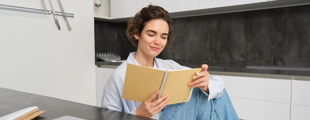 Image d'une fille brune lisant ses notes, écrivant dans un journal, étudiant tout en étant assise à la maison