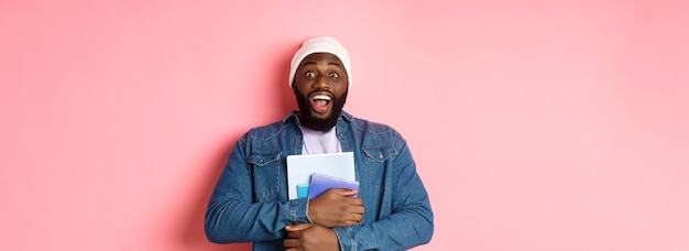 Photo gratuite image d'un homme afro-américain adulte tenant des cahiers et souriant étudiant à des cours debout sur p