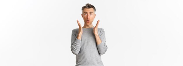 Image d'un homme d'âge moyen aux cheveux courts gris qui a l'air étonné et fasciné en disant wow réagissant à la publicité debout sur fond blanc