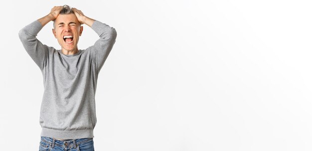 Image d'un homme d'âge moyen frustré, paniqué, perdant quelque chose, déchirant les cheveux sur la tête et grimaçant pour