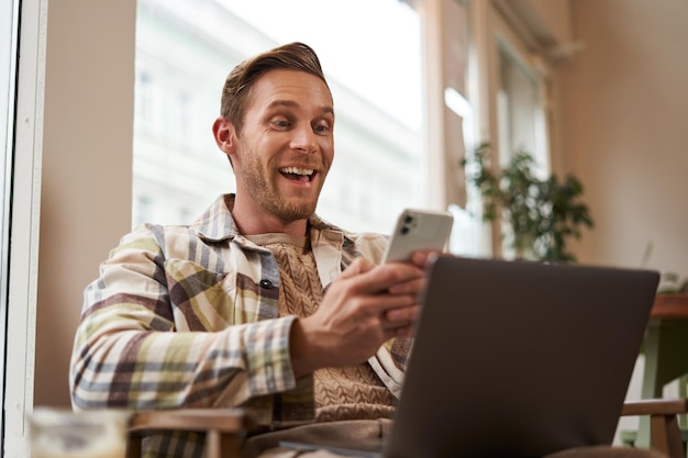 Image d'un homme dans un café, un visiteur d'un café assis dans une chaise avec un ordinateur portable et un smartphone.