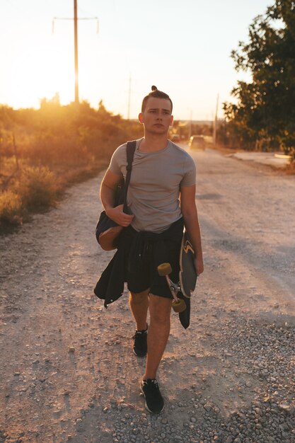 Image d'un homme avec longboard sur route