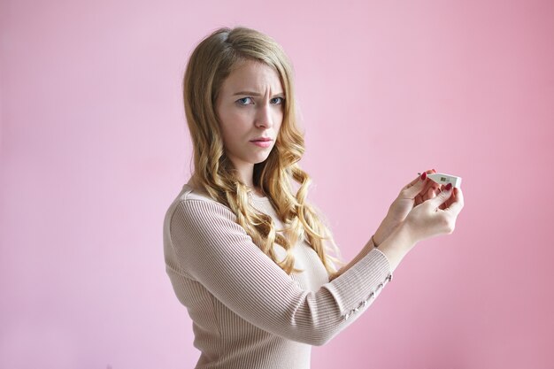 Image horizontale isolée d'une jeune femme européenne contrariée et frustrée avec une coiffure ondulée blonde fronçant les sourcils, se sentant inquiète et effrayée, ayant un test de grossesse positif, pas sûre de sa décision.