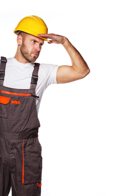 Image d'un ingénieur debout avec un casque jaune et regardant quelque part