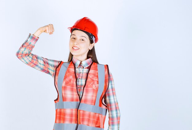 Image de jeune belle femme ingénieur en casque debout avec une expression heureuse.