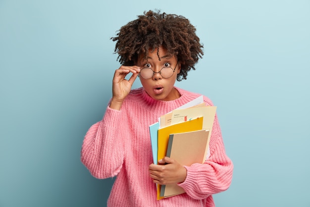 Image d'un jeune enseignant surpris ouvre la bouche comme étant sans voix, tient quelques papiers et bloc-notes