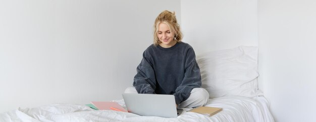 Image d'une jeune étudiante heureuse qui apprend à domicile en ligne se connecte au cours en ligne sur son ordinateur portable
