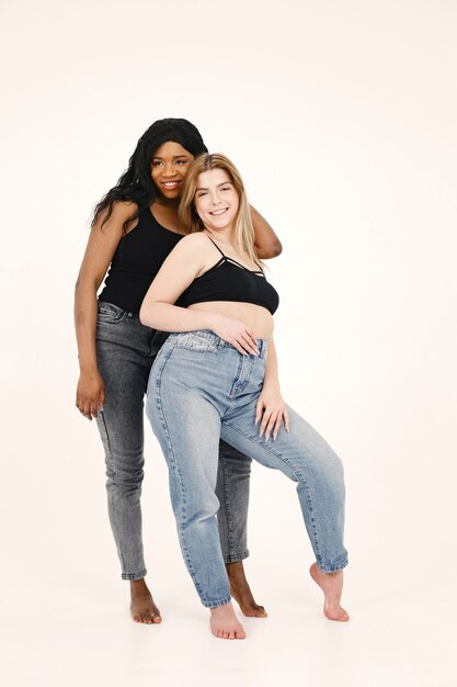 Image d'une jeune femme. Amis multiraciaux posant isolé sur fond de mur blanc.