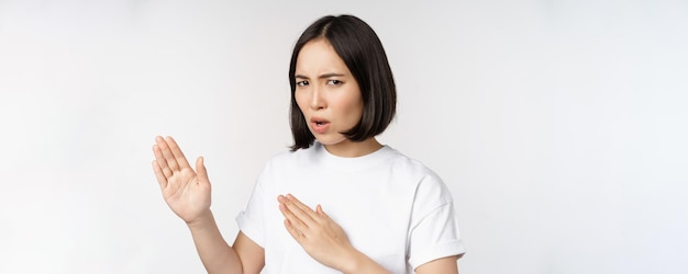 Image d'une jeune femme asiatique impertinente debout dans un combat de karaté pose un combattant d'arts martiaux debout sur fond blanc