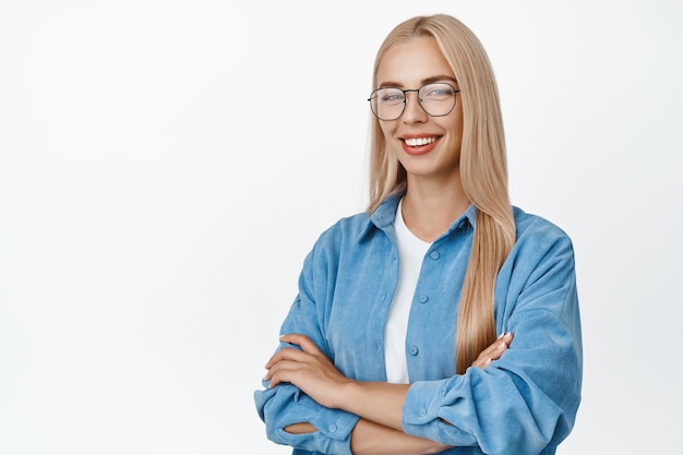 Image d'une jeune femme blonde à lunettes debout comme un professionnel souriant et regardant confiant les bras croisés sur la poitrine debout sur fond blanc