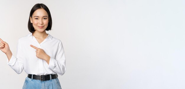 Image d'une jeune femme de bureau souriante, entrepreneur d'affaires asiatique, pointant les doigts vers la gauche, montrant le client