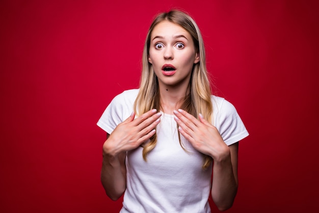 Image d'une jeune femme choquée excitée debout isolée sur un mur rouge.