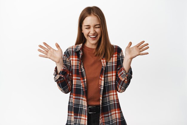 Image d'une jeune femme joyeuse riant, sautant du bonheur et célébrant la victoire, criant de joie, serrant la main, debout sur fond blanc excité.