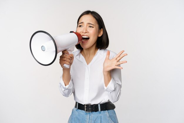 Image d'une jeune femme recruteuse militante coréenne criant dans un mégaphone cherchant à crier au haut-parleur debout sur fond blanc