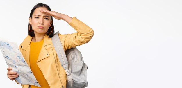 Image d'une jeune fille asiatique voyageur touristique avec carte et sac à dos posant sur fond de studio blanc Espace de copie