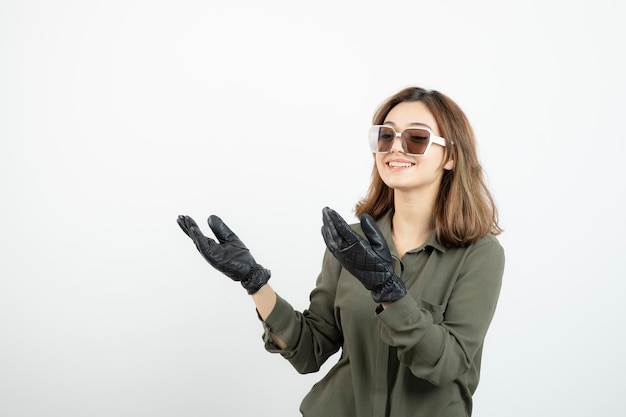 Image de jeune fille à lunettes et gants souriant joyeusement sur blanc. Photo de haute qualité