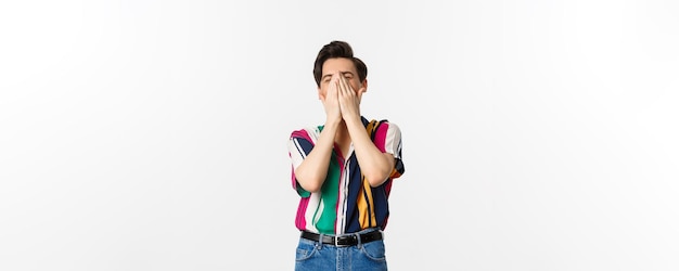 Photo gratuite image de jeune homme élégant éternuant dans les mains debout sur fond blanc