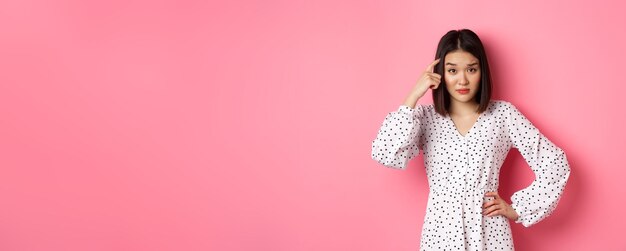 Photo gratuite image d'une jolie femme asiatique grondant une personne pointant vers la tête et regardant la caméra déçue