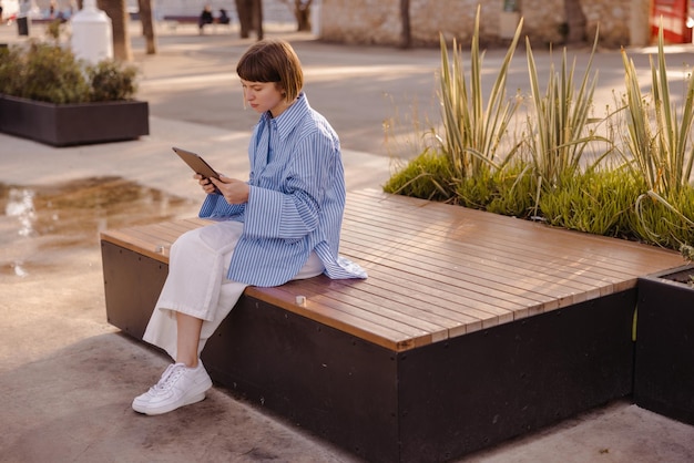 Image de jolie femme assise dans la tablette de lecture du parc