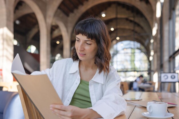 Image de jolie femme tenant des classeurs au café