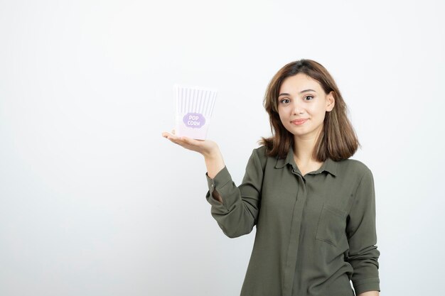 Image de jolie fille avec boîte de pop-corn se présentant à la caméra. Photo de haute qualité