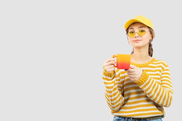 Image de jolie jeune femme dans des verres debout et tenant une tasse. photo de haute qualité