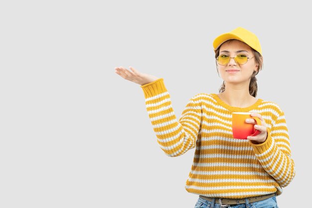 Image de jolie jeune femme dans des verres debout et tenant une tasse. photo de haute qualité