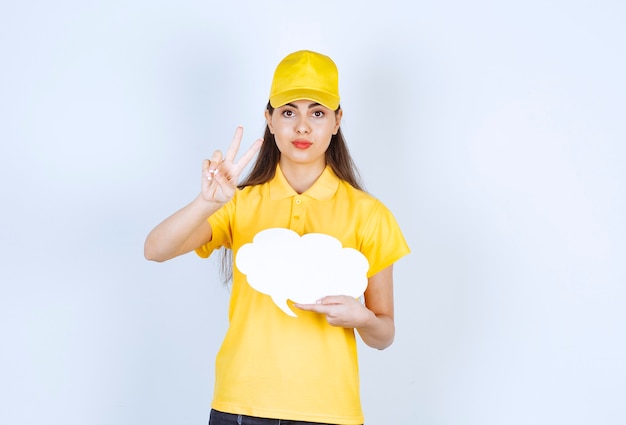 Image d'une livreuse en bonnet jaune posant avec une bulle de dialogue sur un mur blanc.