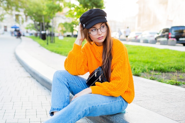 Photo gratuite image de mode de vie en plein air d'une femme rêveuse romantique assise sur le trottoir et profitant de la soirée.