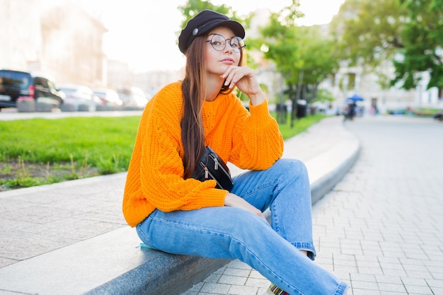 Image de mode de vie en plein air d'une femme rêveuse romantique assise sur le trottoir et profitant de la soirée.