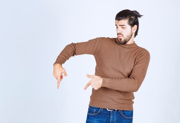 Image d'un modèle de jeune bel homme debout et pointant vers le bas. photo de haute qualité