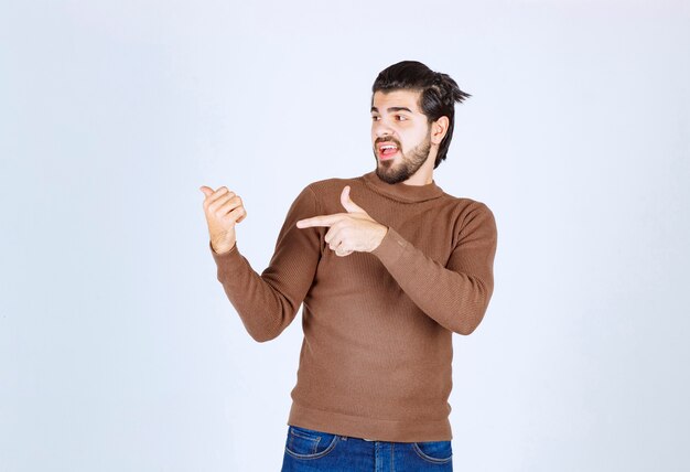 Image d'un modèle de jeune bel homme debout et pointant vers le haut avec les doigts. photo de haute qualité