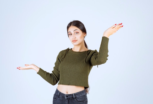 Image d'un modèle de jeune femme souriante pointant vers le haut avec les mains.