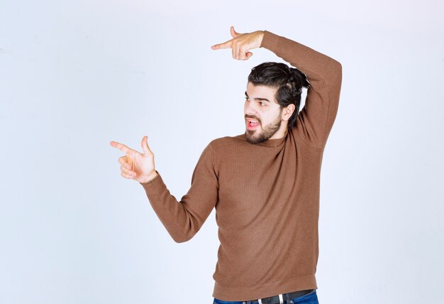 Image d'un modèle de jeune homme beau debout et pointant vers l'extérieur avec les doigts. photo de haute qualité