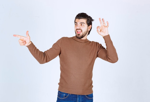 Image d'un modèle de jeune homme souriant debout et pointant vers l'extérieur avec un index. photo de haute qualité