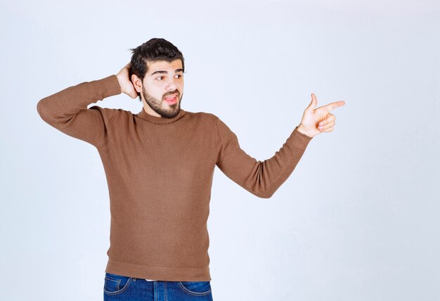 Image d'un modèle de jeune homme souriant debout et pointant vers l'extérieur avec un index. photo de haute qualité