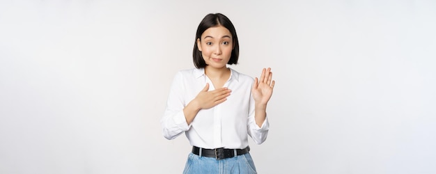 Image of cute young female office worker asian girl student levant la main et mettant la paume sur la poitrine na