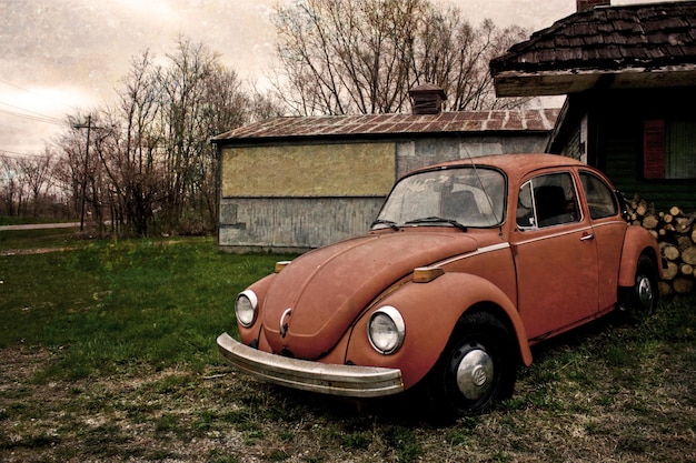 Image d'une photo vintage avec des couleurs atténuées d'une vieille vw beetle avec une maison et des arbres en arrière-plan