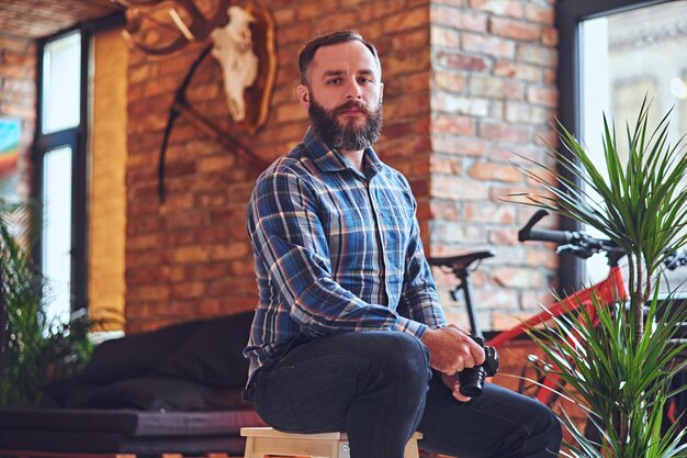 Image d'un photographe amateur hipster barbu prenant des photos dans une pièce avec un intérieur loft.