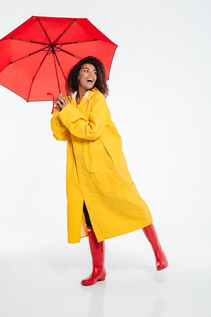 Image pleine longueur de femme africaine heureuse en imperméable posant