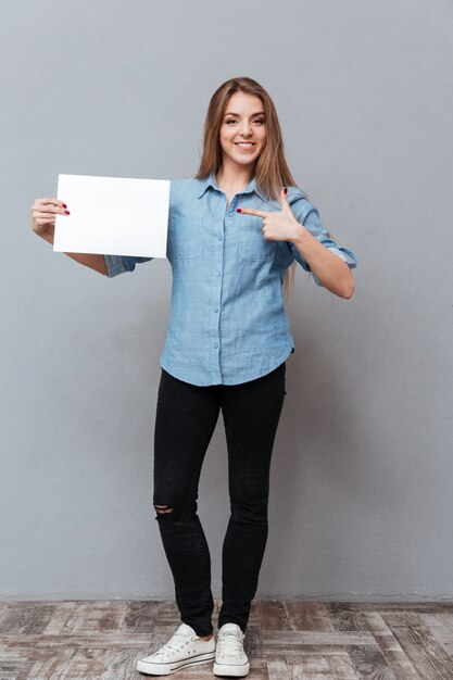 Image pleine longueur de femme en chemise montrant un tableau blanc